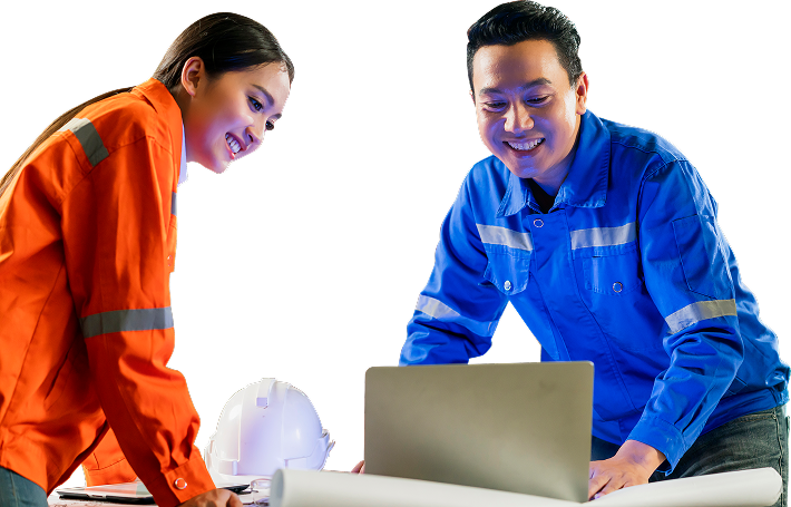 Two engineers wearing helmets, one holding a laptop, smiling in professional setting